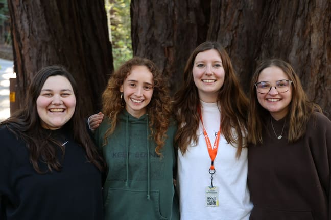 Four Chi Alpha students arm in arm, laughing