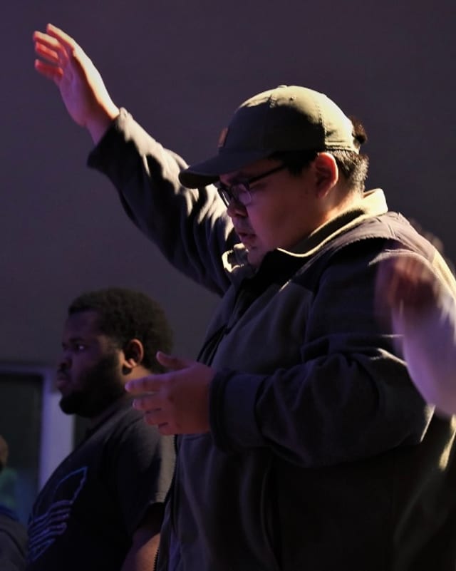 A student with a hand raised during worship
